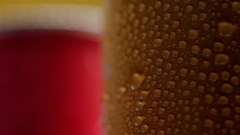 Close-Up-Of-Condensation-Droplets-On-Revolving-Takeaway-Cans-Of-Cold-Beer-Or-Soft-Drinks-Against-Yellow-Background-1